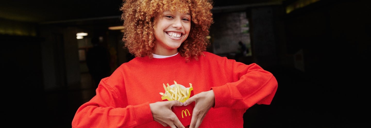Frau formt mit Händen Herz um McDonald's-Pommes
