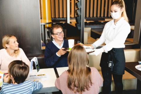 Beim McDonald’s Tischservice bringen MitarbeiterInnen die Bestellung mit Mund-Nasen-Schutz zum Tisch