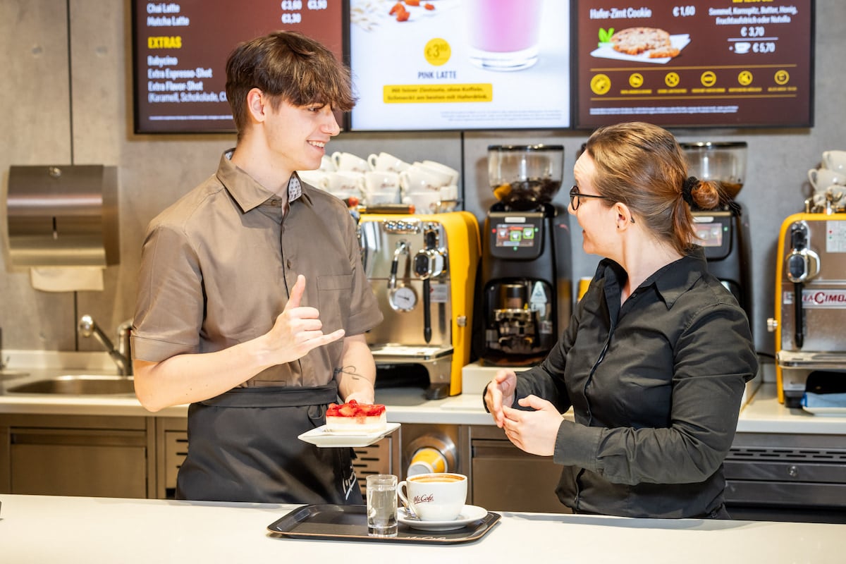 Zwei McDonalds-Mitarbeiter:innen unterhalten sich in Gebärdensprache