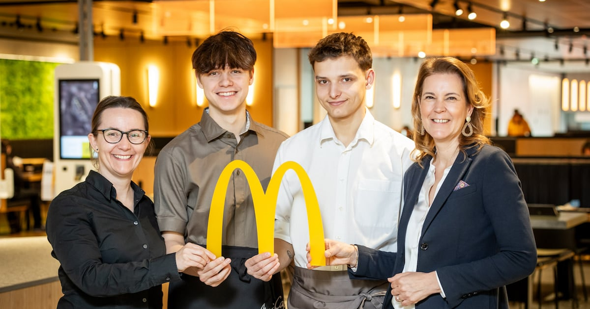 4 lächelnde Personen halten das McDonalds "M" in die Kamera.