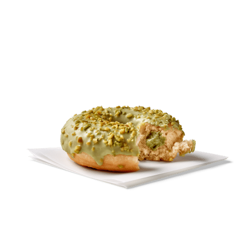 Ein köstlicher Donut mit Pistazienüberzug und einem Biss heraus, auf einem weißen Papier serviert.
