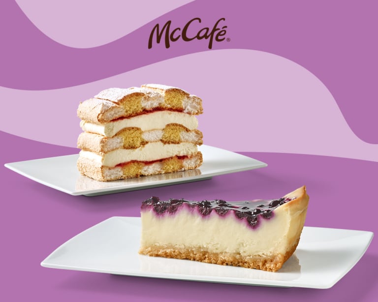Zwei köstliche Desserts von McCafé: ein schichtiger Kuchen und ein Käsekuchen mit Heidelbeer-Topping.
