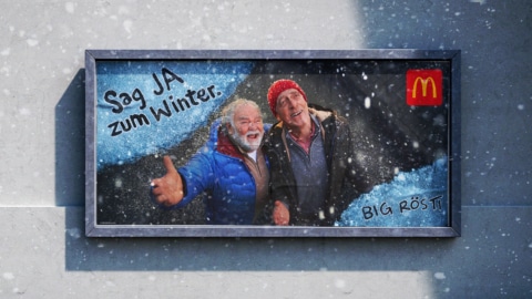 Werbung von McDonald's mit zwei Männern, die im Winter einen frohen Moment im Schnee genießen.