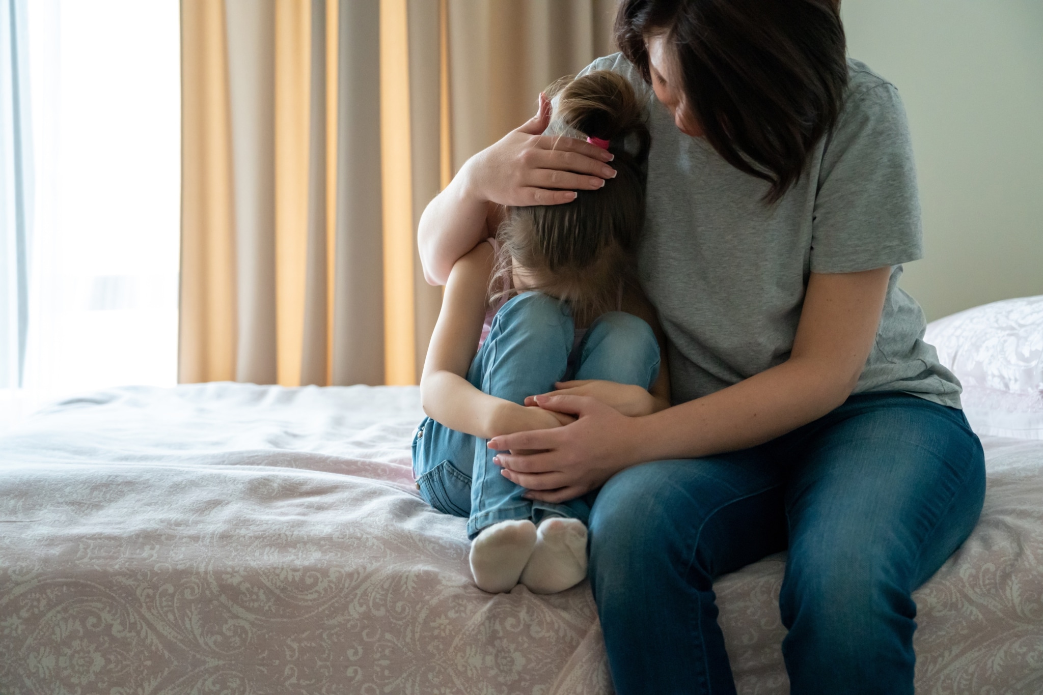 Fürsorgliche Mutter tröstet und umarmt ihre Tochter.